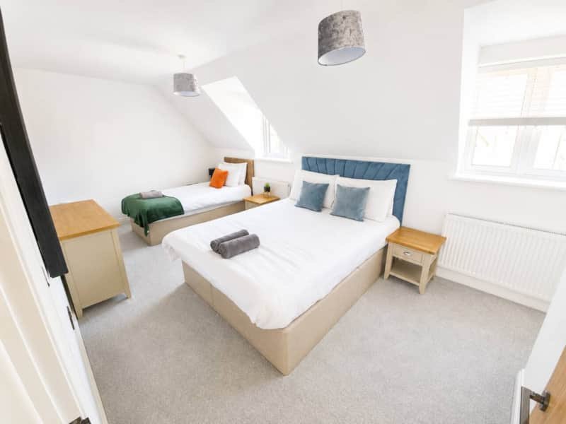 Bright bedroom with two beds, wooden nightstands, blue headboard and pendant lights