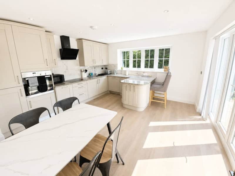 Modern open-plan kitchen and dining area with cream cabinetry, island, and garden views