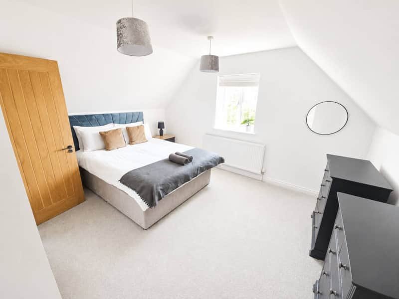 Bright attic bedroom with double bed, wooden door, window and modern furnishings