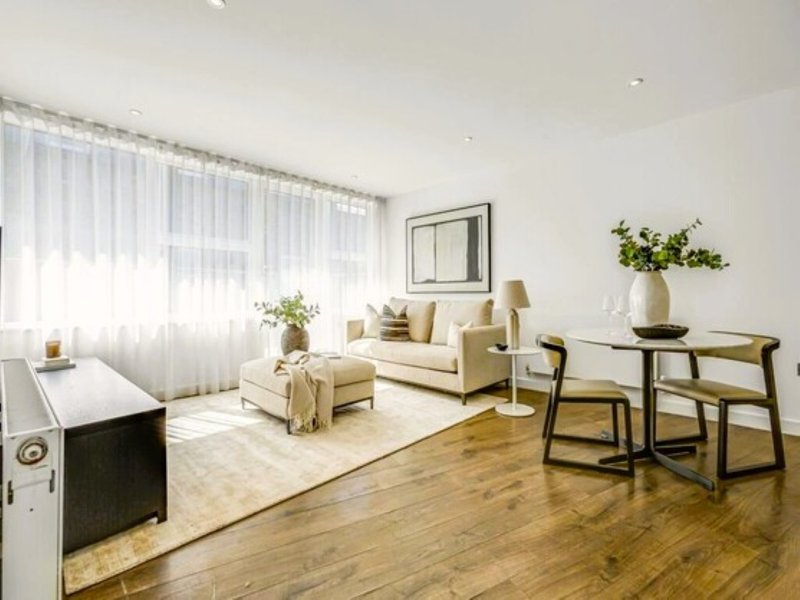 Modern living room with cream sofa, dining table, wooden floors and large windows