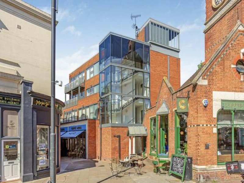 Street-level exterior view of brick buildings with modern glass extension and ground-floor storefronts