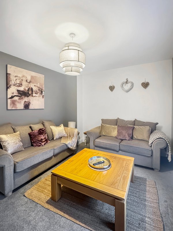 Living room with two grey sofas, yellow coffee table, pendant light, and wall art