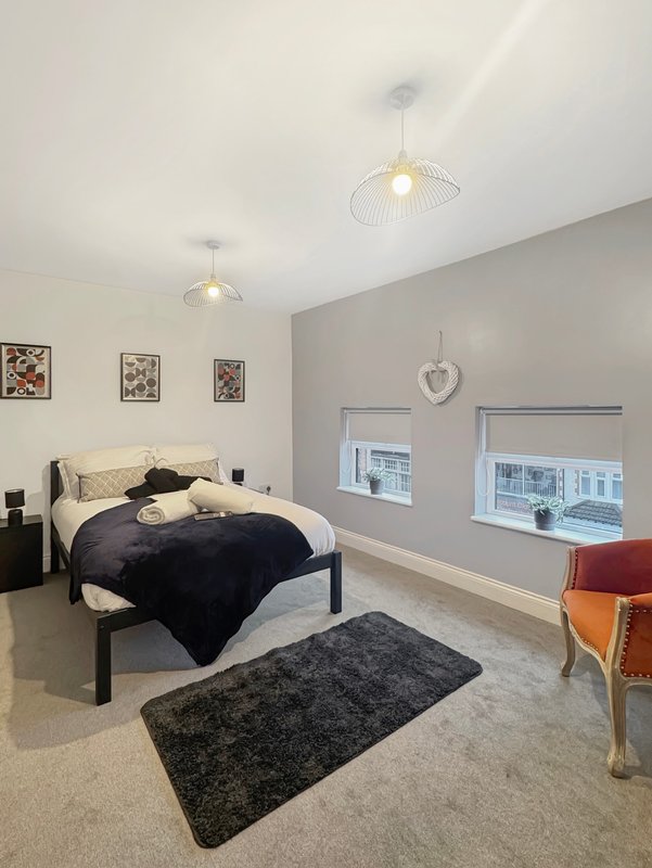 Modern bedroom with double bed, pendant lights, grey accent wall and windows