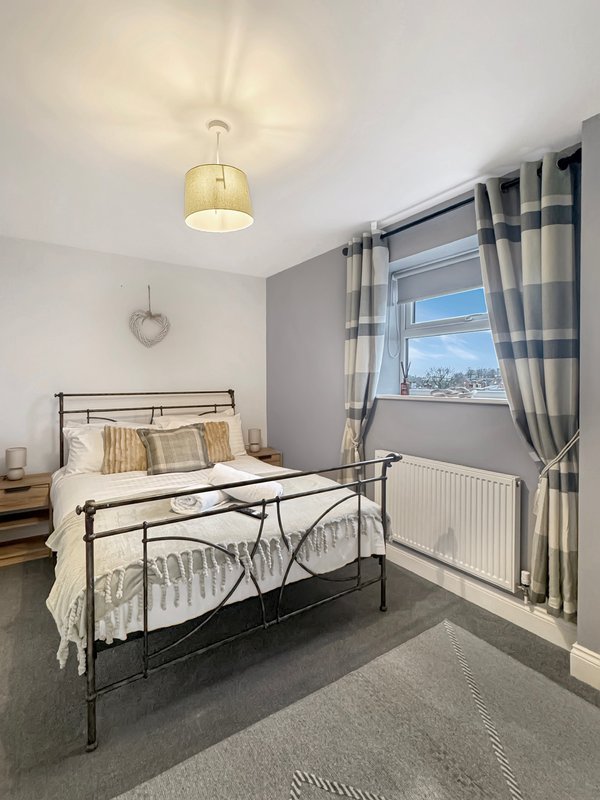 Bright bedroom with metal bed frame, striped curtains, pendant light and window view