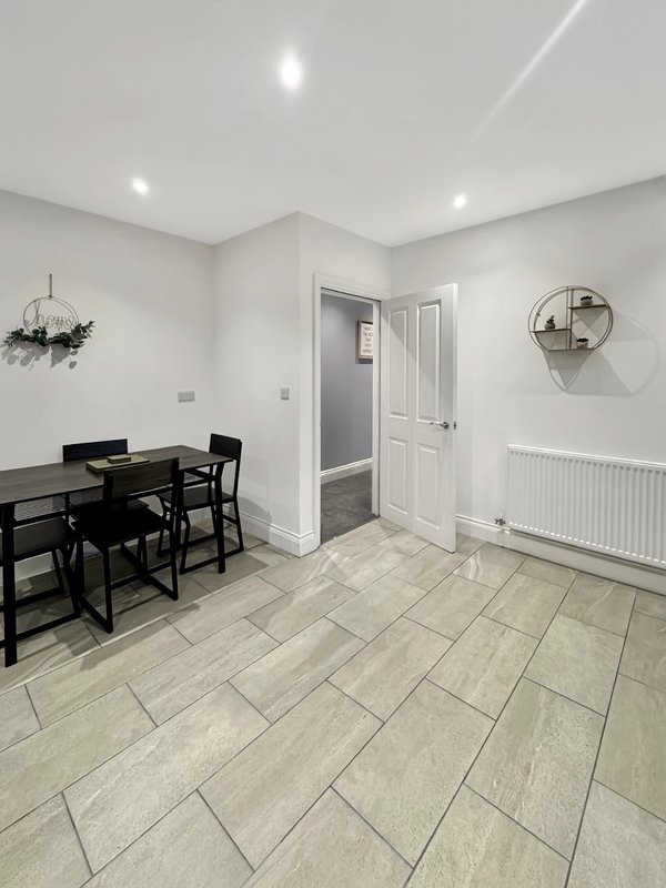 Modern kitchen-diner with black table, tiled flooring, white doors and radiator