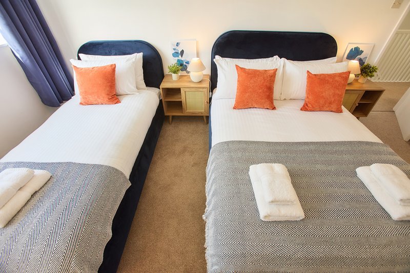 Twin bedroom with two beds, orange cushions, wooden nightstands and warm lighting