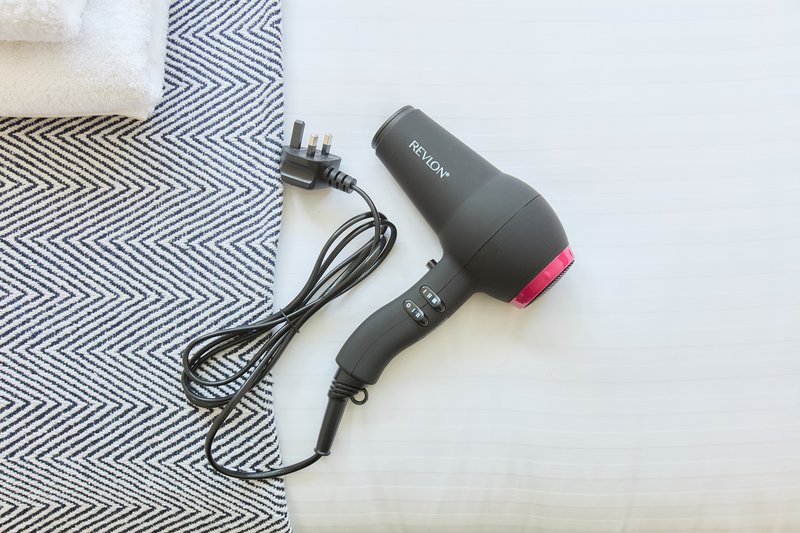 Black hair dryer with pink accents on geometric patterned towel