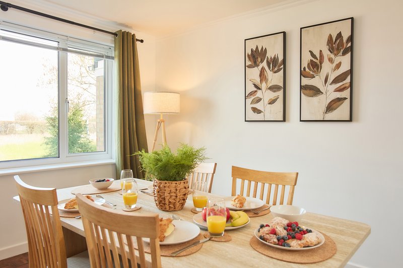 Dining room with wooden table, chairs, place settings, fruit bowl and orange juice glasses