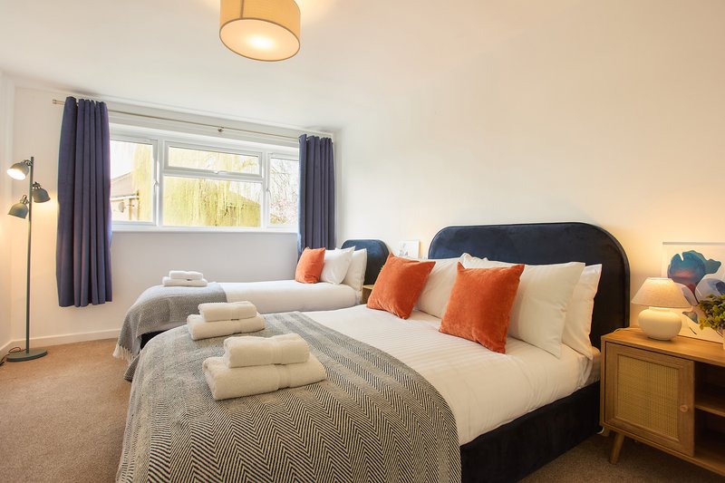 Spacious bedroom with double bed, colorful cushions, wooden nightstand and floor lamp
