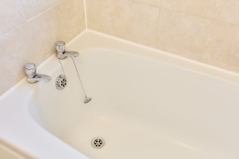 Clean white bathtub with chrome faucet, handles, and shower head