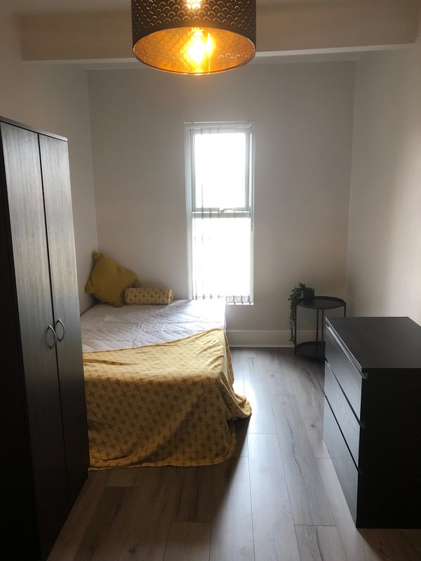 Bright bedroom with single bed, yellow bedding, wooden floor, and pendant light fixture