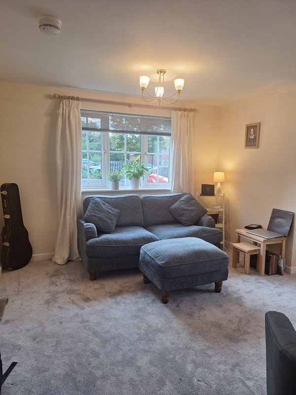 Living room with gray sofa, ottoman, window with curtains, side table and pendant lighting