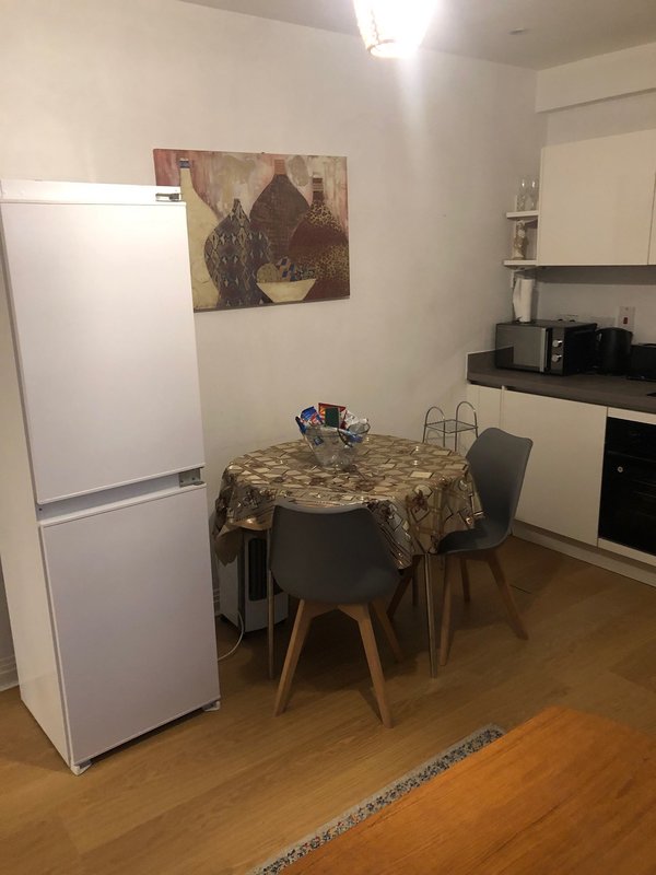 Kitchen with white fridge, round dining table, chairs, and wall-mounted artwork