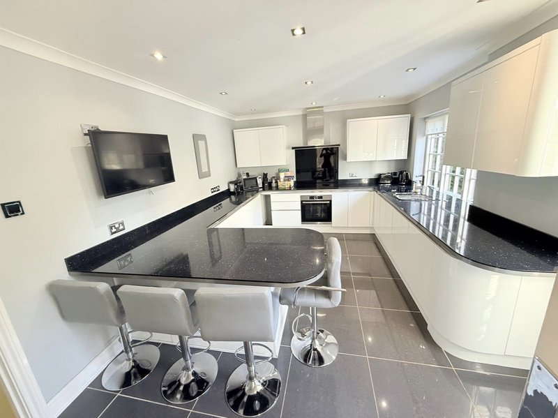 Modern kitchen with white cabinetry, black granite counters, island with seating, and wall-mounted television