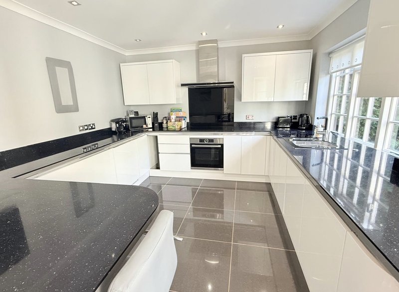 Modern kitchen with cream cabinets, black worktops, built-in appliances and tiled floor
