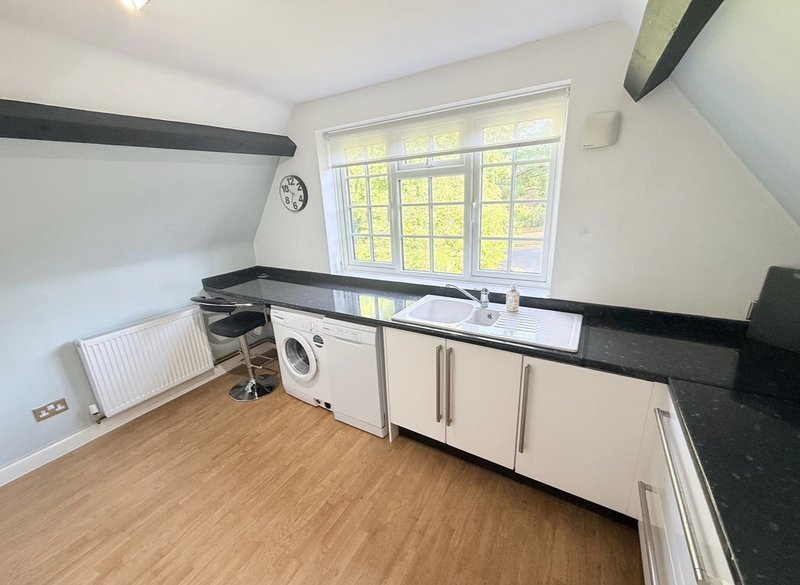 Utility room with washing machine, sink, black countertop and large window with garden view