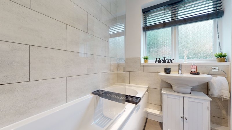 Modern bathroom with bathtub, shower enclosure, white vanity and window blinds