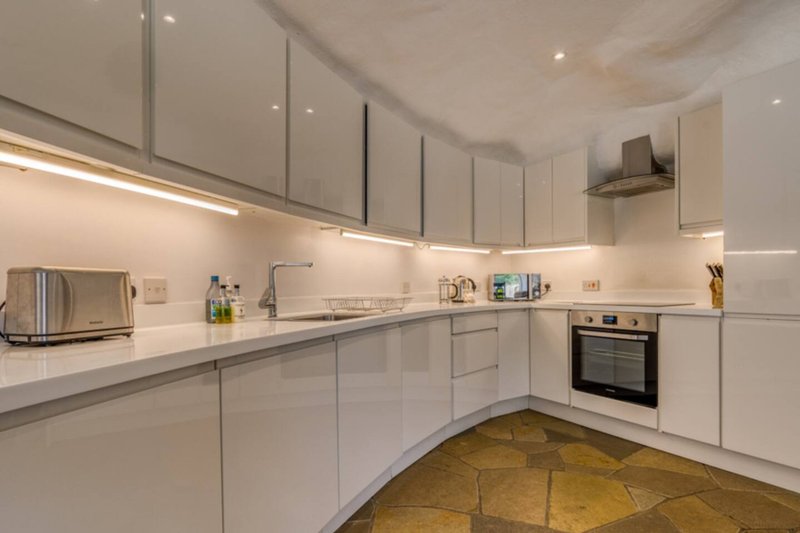 Modern white kitchen with fitted cabinets, stainless steel appliances and geometric floor