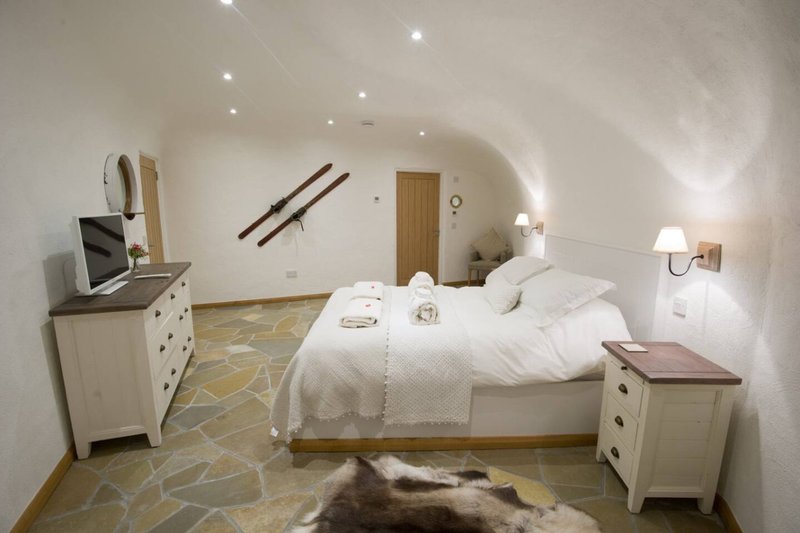 Spacious attic bedroom with sloped ceiling, white furnishings, double bed and wooden flooring
