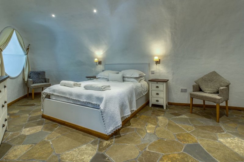 Spacious bedroom with double bed, wooden nightstands, wall sconces, mirror and chair