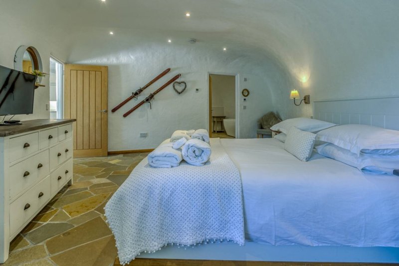 Bright attic bedroom with two single beds, cream dresser, wooden door and sloped ceiling
