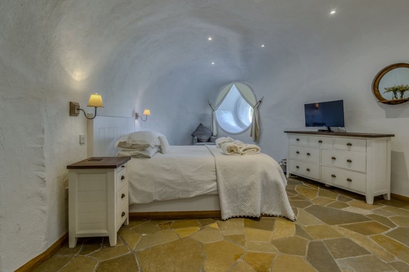 Bedroom with arched ceiling, double bed, white furniture, and geometric floor tiles