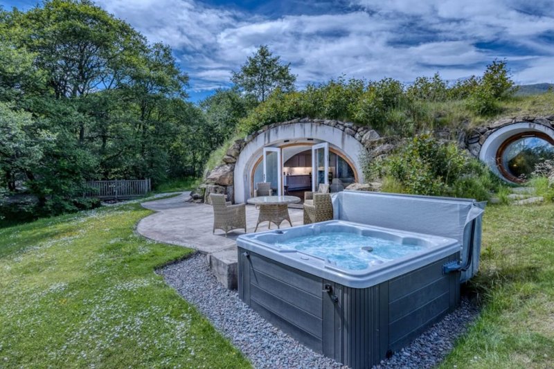 Glamping pod with hot tub surrounded by trees and countryside landscape