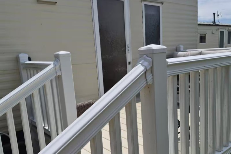 White composite deck railing with steps leading to residential property entrance doors