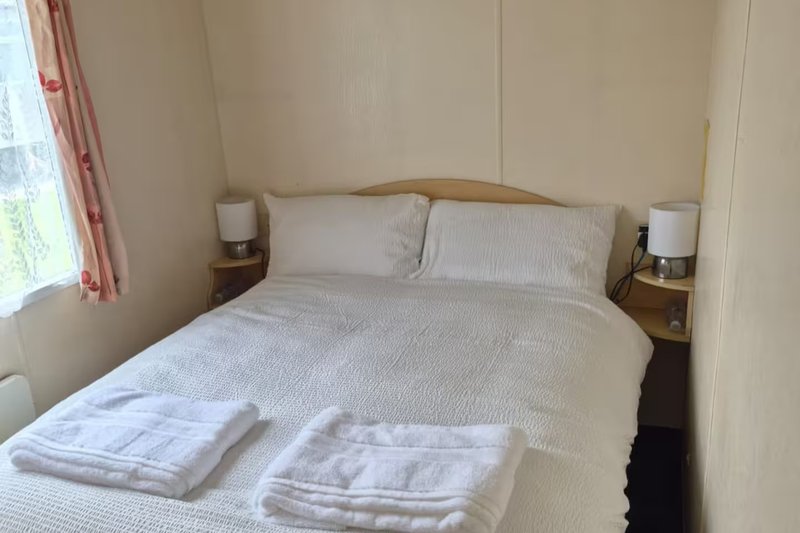 Bright bedroom with double bed, white bedding, wooden headboard and matching bedside tables