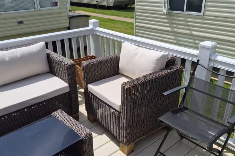 Outdoor deck with wicker seating, cushions, small table and railing