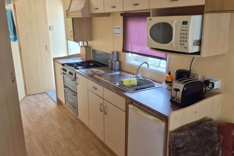 Kitchen with cream cabinets, stainless steel appliances, microwave, and wooden flooring