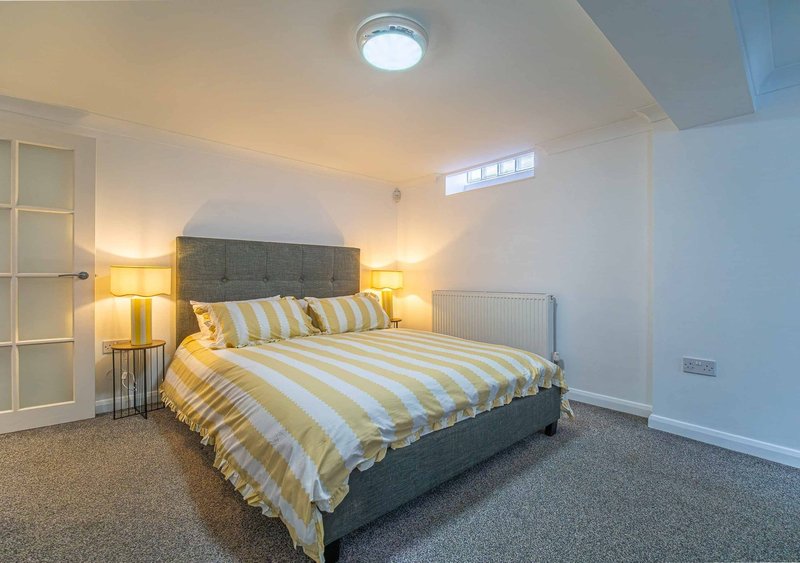 Bright bedroom with double bed, yellow striped bedding, twin bedside lamps and sloped ceiling