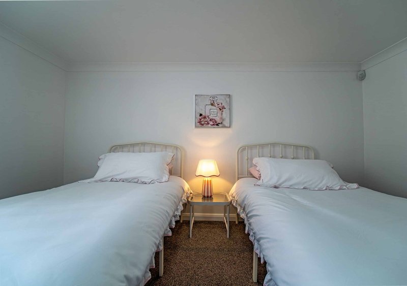 Twin bedroom with two single beds, bedside table with lamp, and wall art