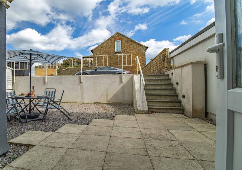 Paved courtyard with outdoor seating, stone wall, and stone terraced house backdrop