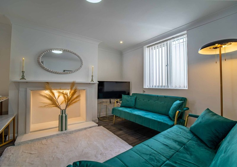 Modern living room with teal sofa, fireplace with decorative vase, wall mirror and floor lamp