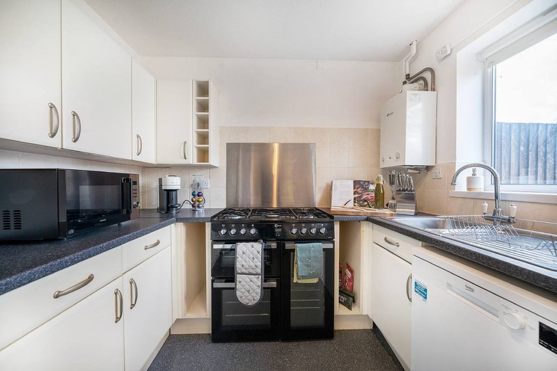 Modern kitchen with white cabinetry, black range cooker, stainless steel appliances and blue worktops