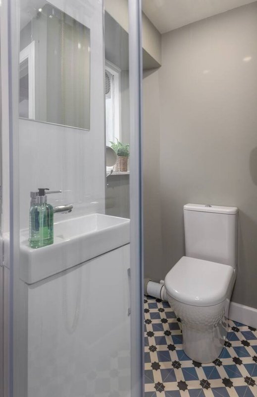 Modern bathroom with white vanity, mirror, toilet, and blue checkered floor tiles