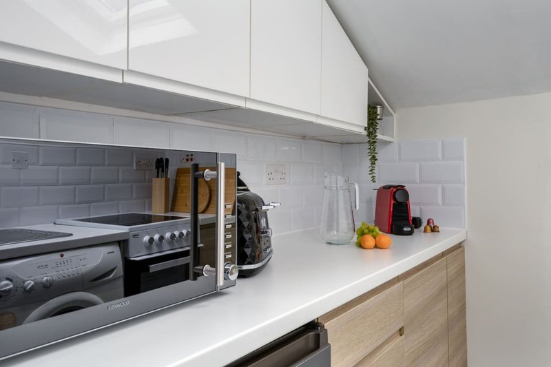 Modern kitchen with white cabinets, subway tile backsplash, gas range, and wooden base units