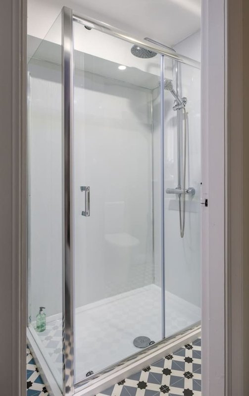 Modern bathroom with glass-enclosed shower cubicle and black-and-white tile flooring