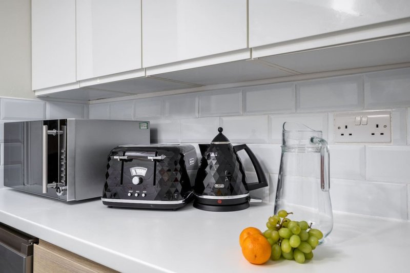 Modern kitchen counter with appliances, kettle, toaster and fresh fruit displayed