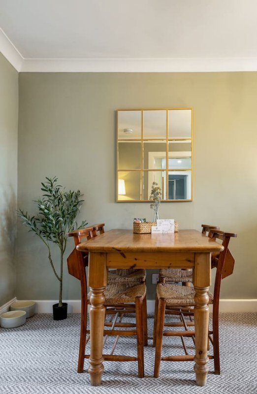 Dining room with wooden table, two chairs, potted plant and mirror on wall