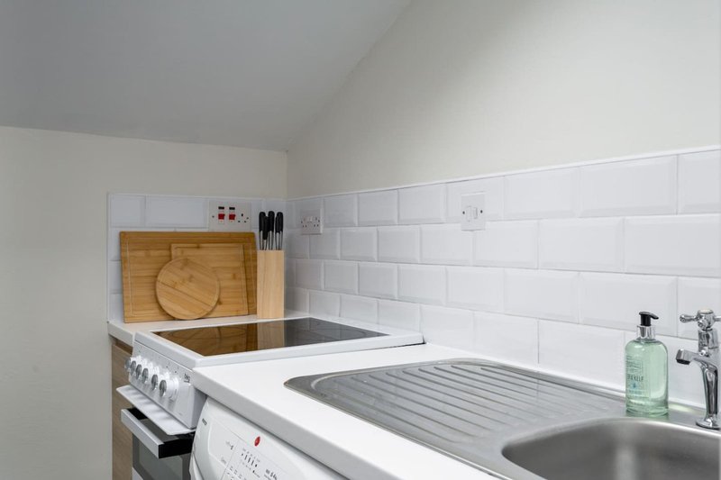 Modern kitchen with white subway tiles, stainless steel sink and cooker, wooden chopping board
