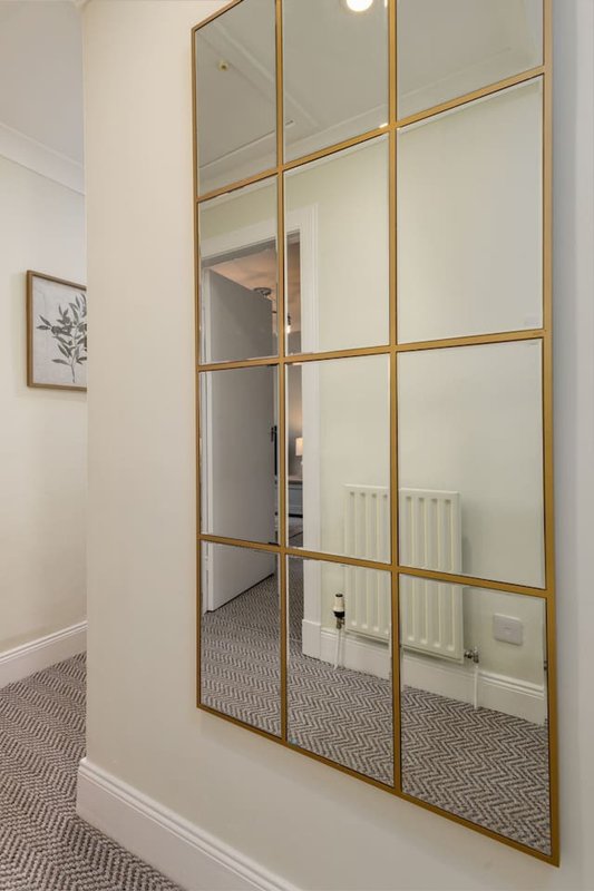 Hallway with large brass-framed mirror reflecting interior rooms and white radiator