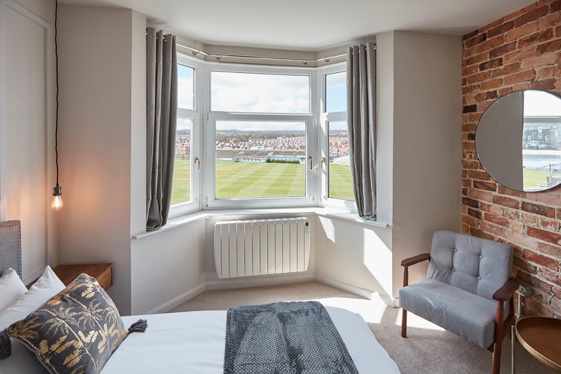 Bedroom with bay window, city view, exposed brick wall and seating area