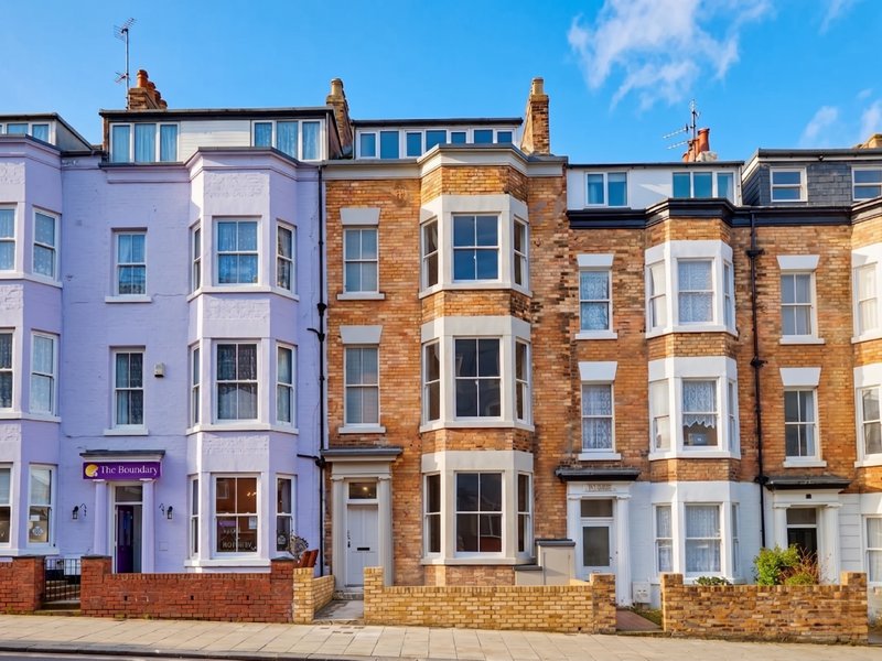 Colorful Victorian terraced townhouses with bay windows and brick facades on a street