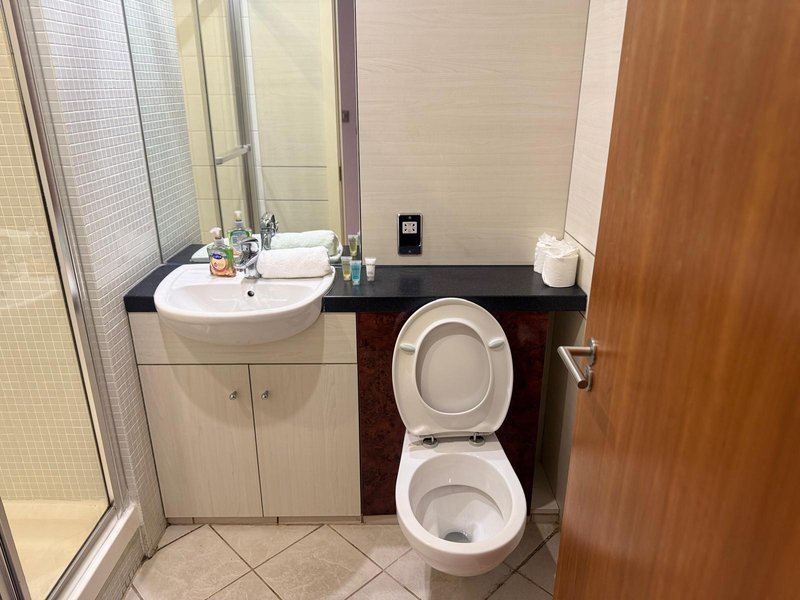 Bathroom with curved sink, toilet, mirror, shower enclosure and wooden door