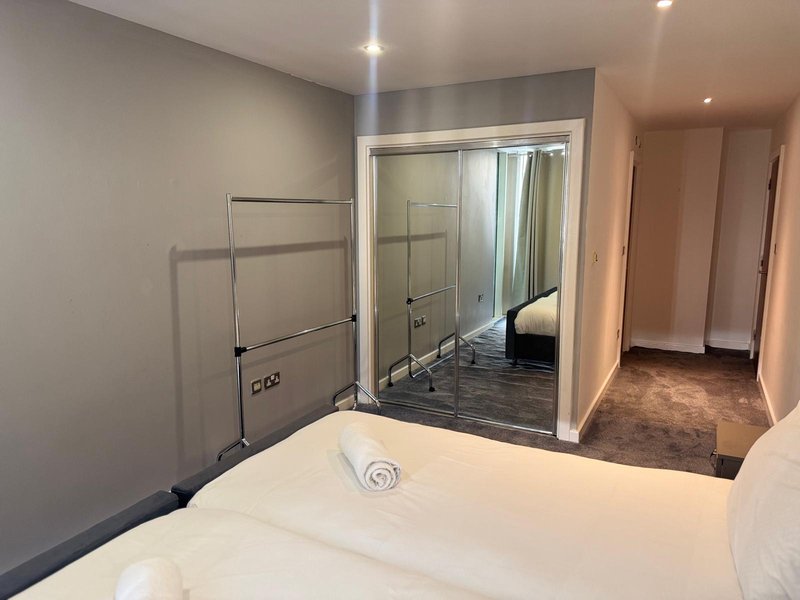 Bedroom with double bed, ensuite bathroom with shower enclosure and dark tile floor
