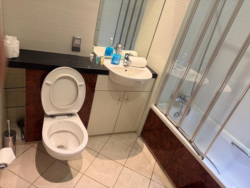 Bathroom with toilet, sink, mirror, and shower enclosure with striped doors