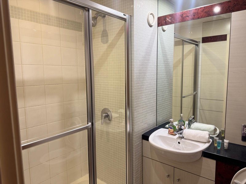 Bathroom with double sink vanity, mirror, shower enclosure and tiled walls