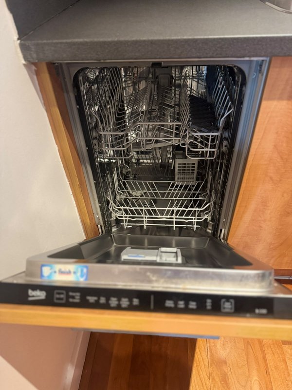 Integrated dishwasher with open door showing interior racks and controls